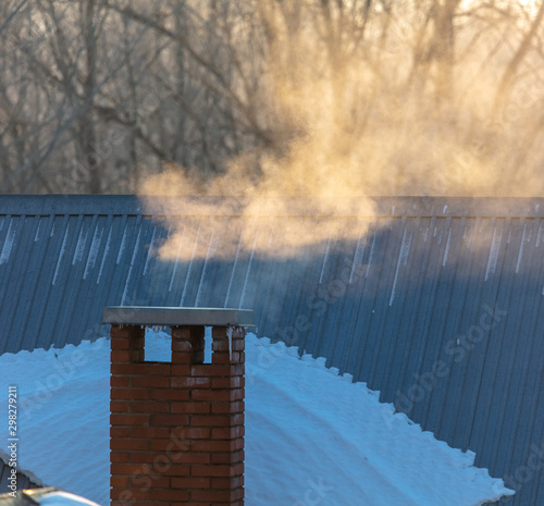 Smoke from the chimney of a house at dawn of the sun