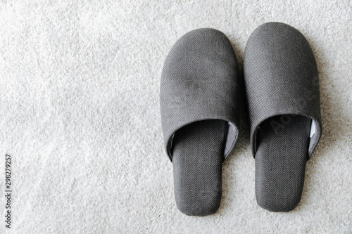 Top view gray fluffy slippers separate on the white fur rug
