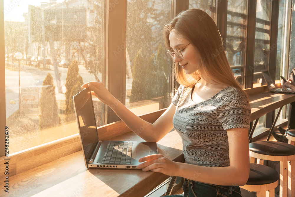 young beautiful girl in a coffee working on a laptop,space for text on the screen young beautiful girl in a coffee working on a laptop,space for text on the screen