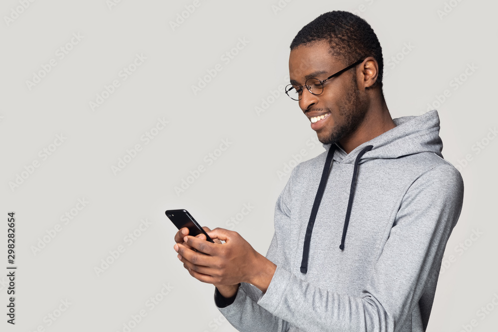 Side view smiling African American man using phone, chatting online Side view smiling African American man using phone, chatting online
