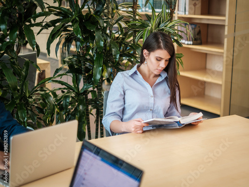 Young woman reading book in public library