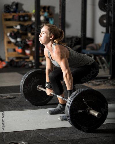 Young female weight lifter preparing for heavy barbell lift. photo