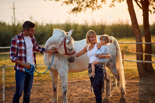 Family with girl petting horses in countryside