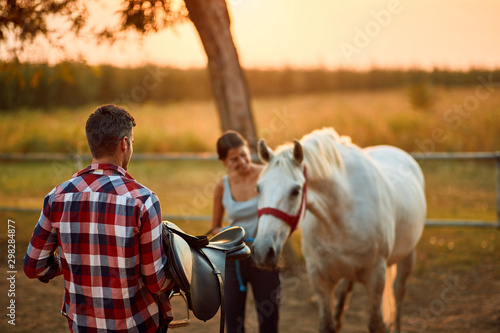  man and woman with horse at ranch. Saddling a horse.
