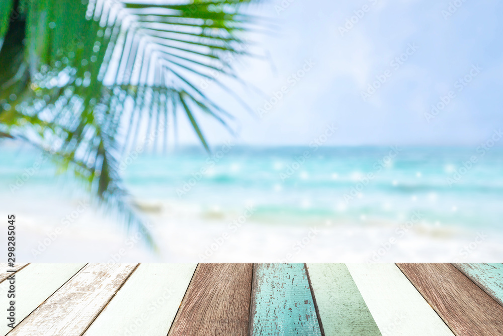 Fototapeta premium Paint wood with blur of beautiful view of blue sea and white beach and coconut leaves.