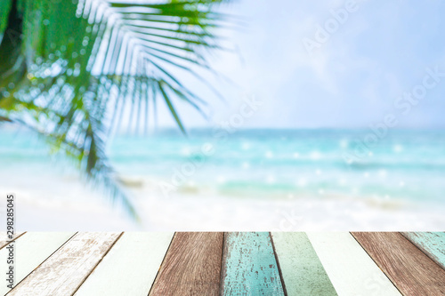 Paint wood with blur of beautiful view of  blue sea and white beach and coconut leaves.