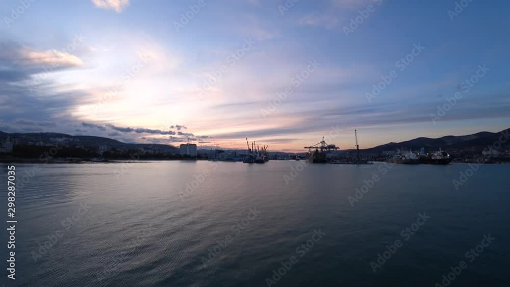 View on seaport and loading docks at the port with cranes and cargo containers during sunset View on seaport and loading docks at the port with cranes and cargo containers during sunset