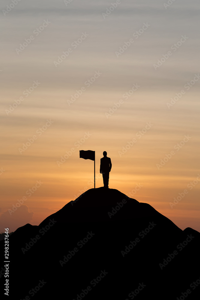 Silhouette of businessman raising his hand to celebrate success on top mountain, sky and sun light background.