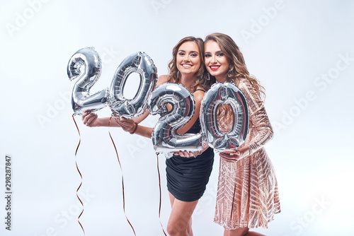 Canvas Print Happy young women in dresses with metallic foil 2020 balloons on white background