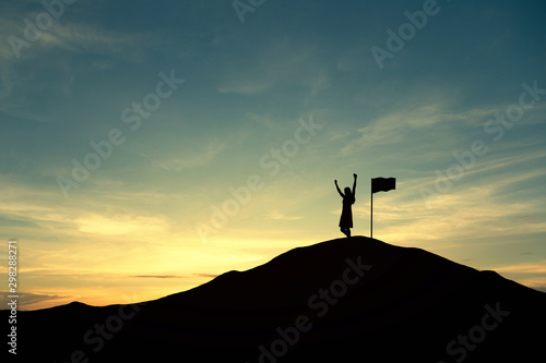 Silhouette of people and flag on top mountain, sky and sun light background. Business success and goal concept.