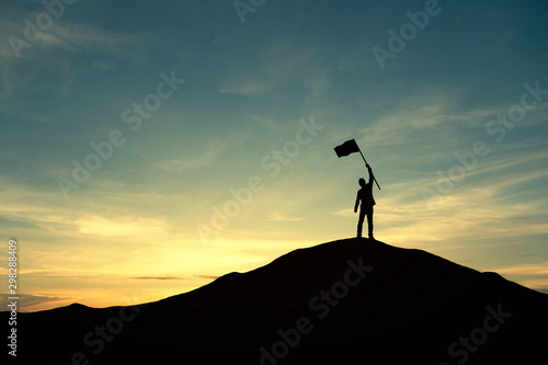 Silhouette of people and flag on top mountain, sky and sun light background. Business success and goal concept.