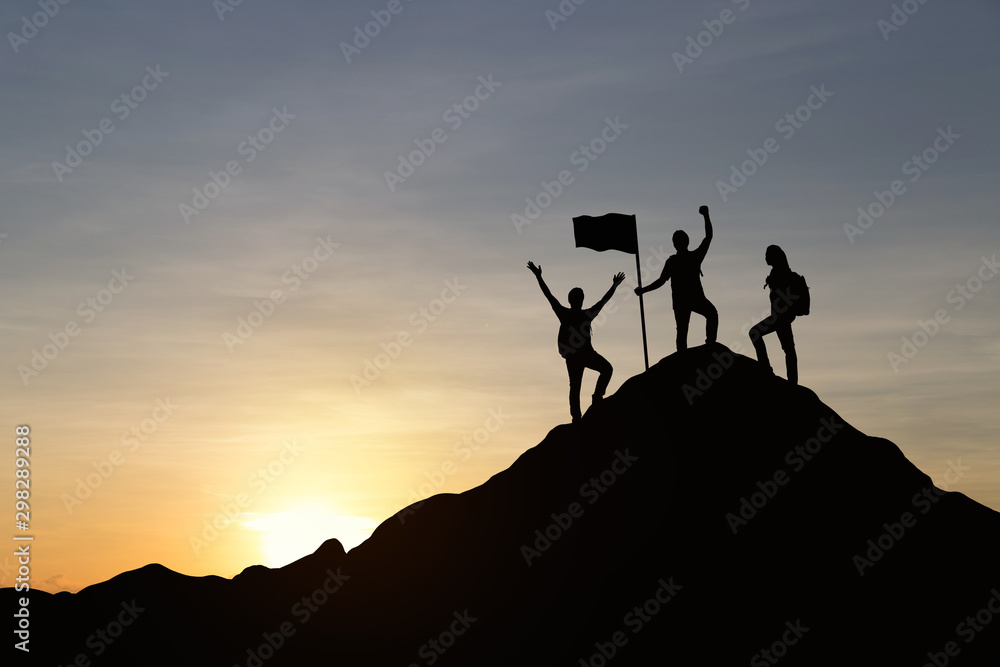 Silhouette of people are celebrating success at the top of the mountain, sky and sun light background. Team business concept.