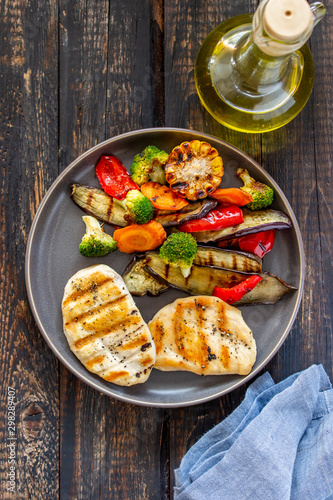 Grilled chicken with grilled vegetables on a wooden background. Healthy eating.