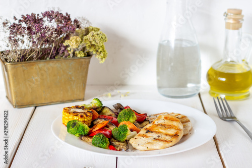 Grilled chicken with grilled vegetables on a wooden background. Healthy eating.