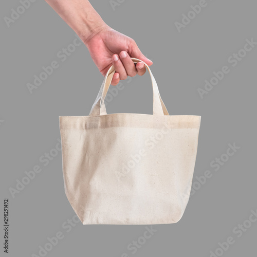 Tote bag canvas white cotton fabric cloth for eco shoulder shopping sack mockup blank template isolated on grey background (clipping path) with woman’s hand handling handle straps