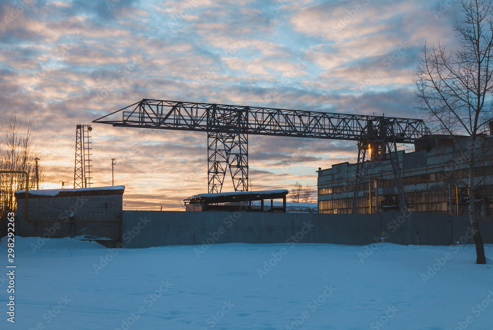 Rail mounted crane at the plant behind a fence in winter landscape. Yoshkar-Ola city, Mari El, Russian Federation