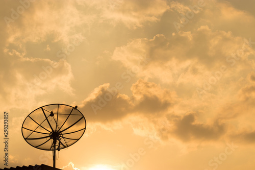 The satellite dish has a background in the sky and evening clouds with a beautiful golden orange glow.