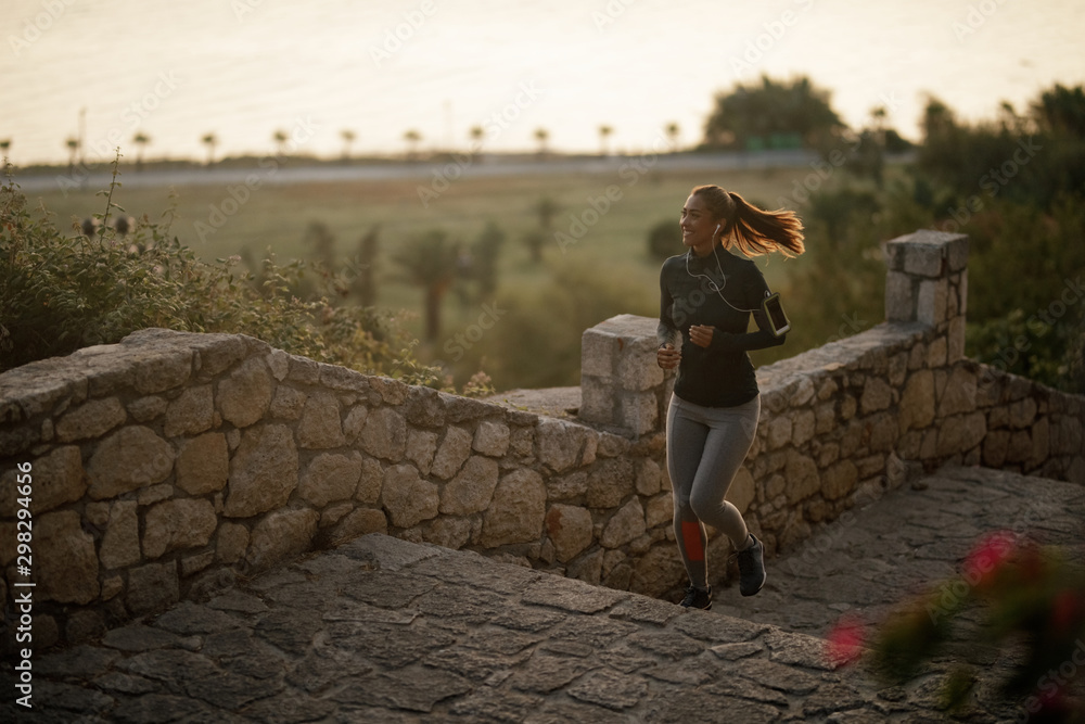 Fototapeta premium Young happy sportswoman jogging in nature.