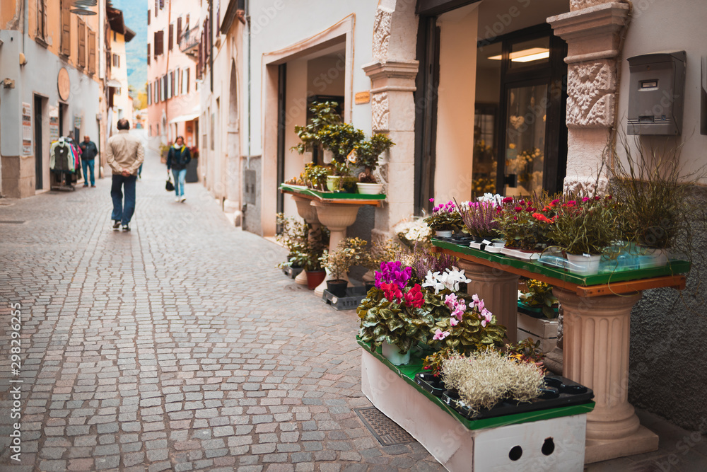 Obraz premium Flowers on an old Italian street in the city of Arco in focus. Street background blurred