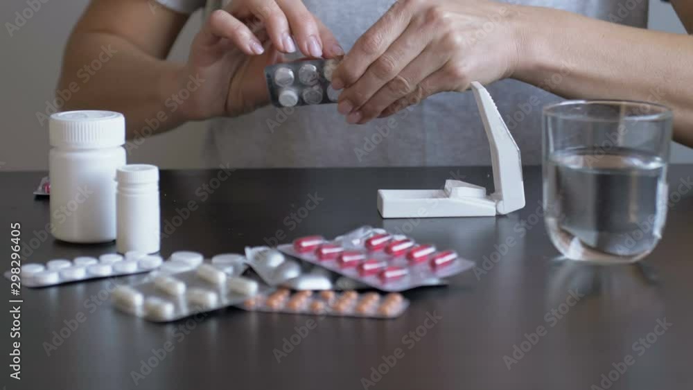 Woman taking medicine and using a pill cutter. Taking pills for
