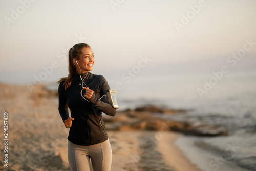 Valokuvatapetti Happy dedicated sportswoman jogging at the beach.