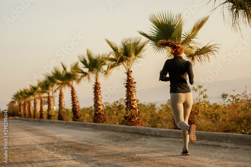 Fényképezés Rear view of determined athletic woman running outdoors.