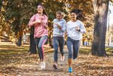 Group of female friends jogging at the city park.Autumn season.