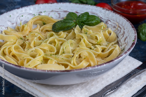 Italian pasta, spaghetti with avocado, spinach, basil, cream, cheese. Vegetarian vegetable pasta. Spinach with noodles. On a light background. Nearby are cherry tomatoes, olive oil. Copy space. 