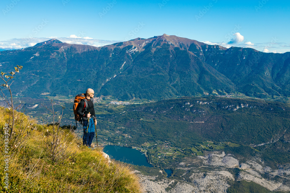 A man traveler with a backpack stands on a hill of beautiful alpine landscape A man traveler with a backpack stands on a hill of beautiful alpine landscape