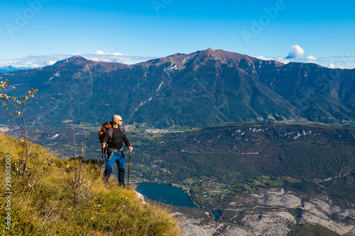 A man traveler with a backpack stands on a hill of beautiful alpine landscape