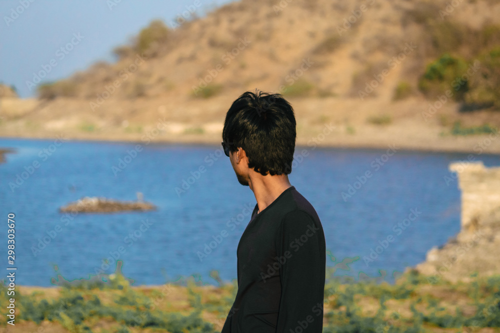 Indian male standing besides the lake