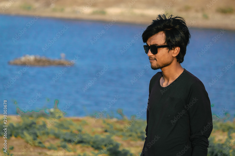 Indian male standing besides the lake