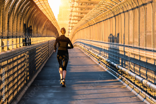 Healthy woman runer in sportsware running exercise morning sunlight sky at Sydney harbour bridge, Australia.