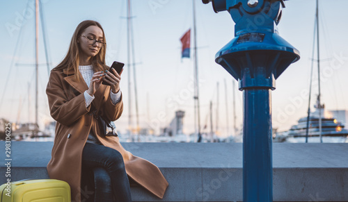 Valokuva Traveler woman with suitcase calling mobile phone in evening port Barcelona