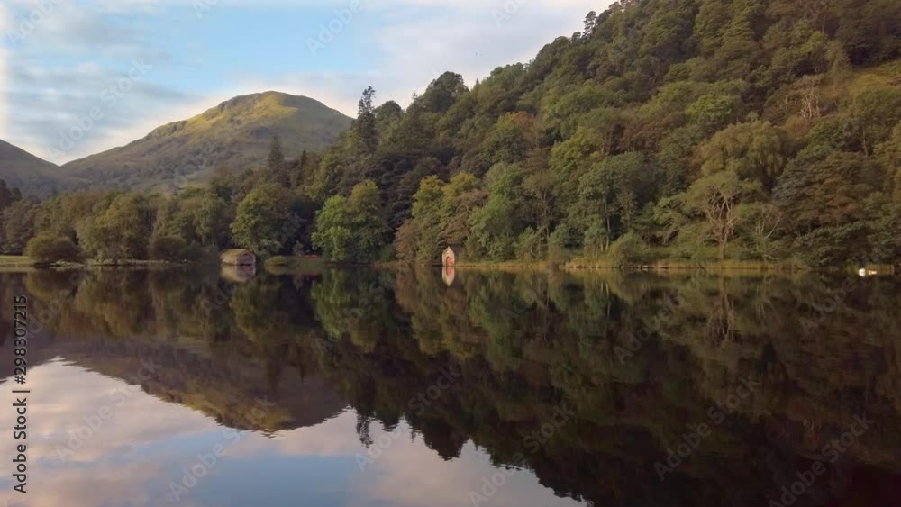 Mirror reflection of hills, woods and boathouses on Ullswater lake Mirror reflection of hills, woods and boathouses on Ullswater lake