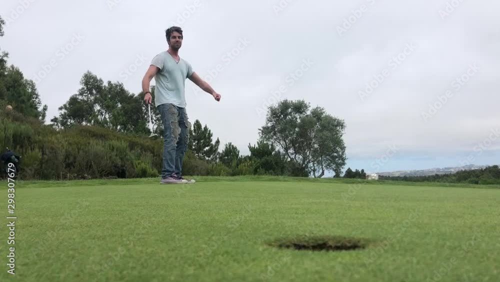Young man on golf green making a long put, hole in one, celebrating and cheering Young man on golf green making a long put, hole in one, celebrating and cheering