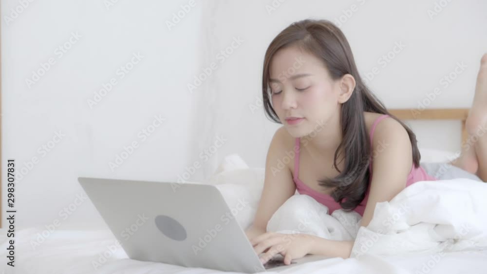 Portrait of beautiful asian young woman sitting on bed using laptop computer at bedroom for leisure and relax, freelance with girl working notebook, communication and lifestyle concept, slow motion. Portrait of beautiful asian young woman sitting on bed using laptop computer at bedroom for leisure and relax, freelance with girl working notebook, communication and lifestyle concept, slow motion.