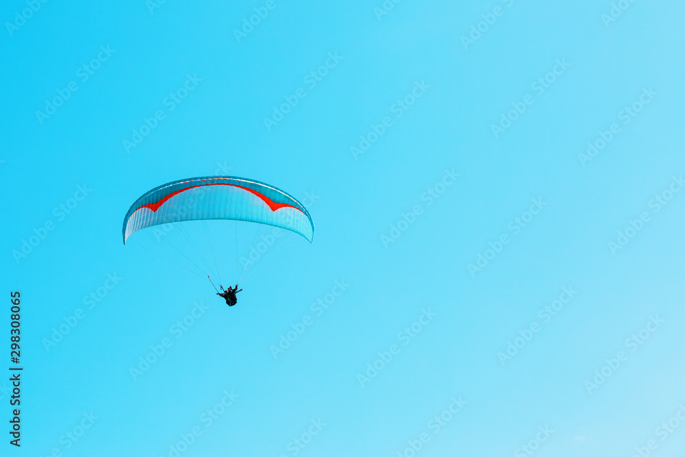 Paraglider soars against the blue sky with clear space.