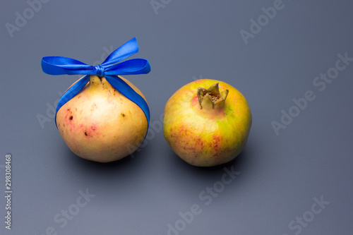 Fruta de Granada con un lazo azul como si fuese un regalo; fruta llena de vitaminas y antioxidantes photo