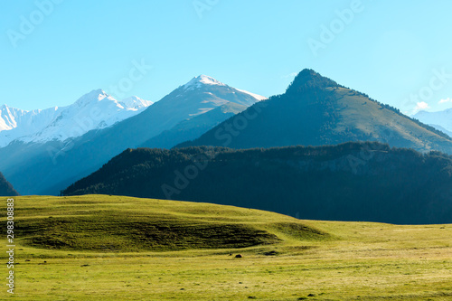 Foggy mountain sunrise. Blue clear sky over the mountains and green meadow. Colorful travel background.