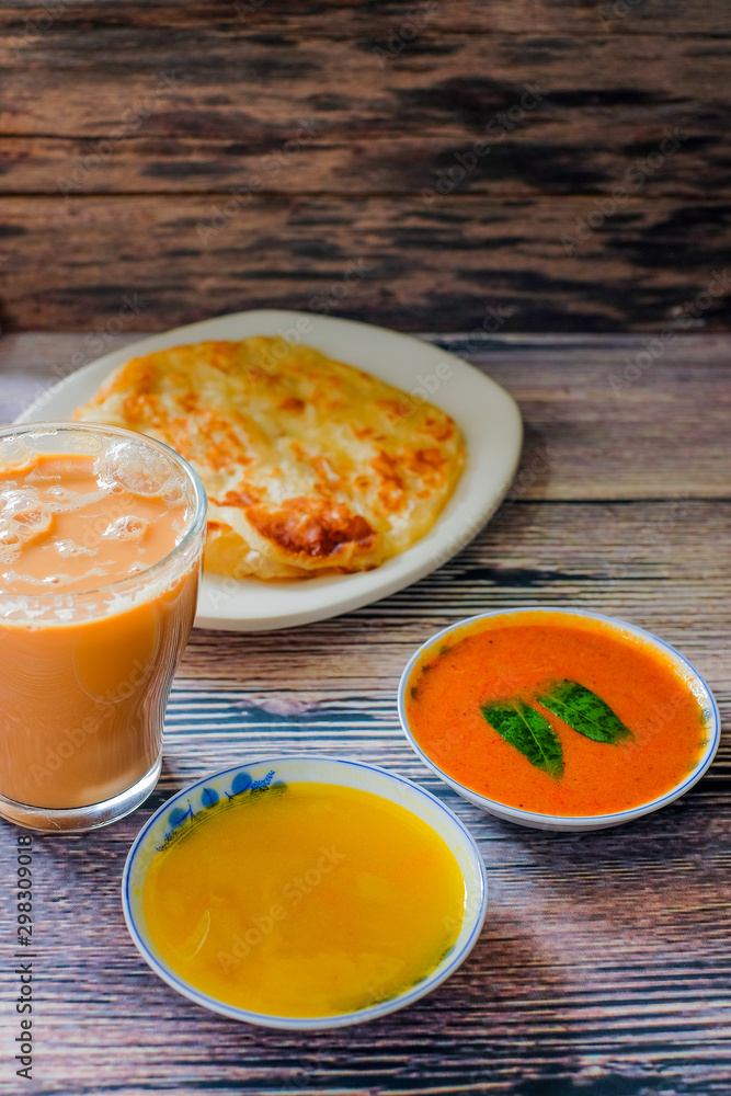 A cup of hot coffee , Roti canai or Roti Parata , dalca and curry sauce on wood background A cup of hot coffee , Roti canai or Roti Parata , dalca and curry sauce on wood background