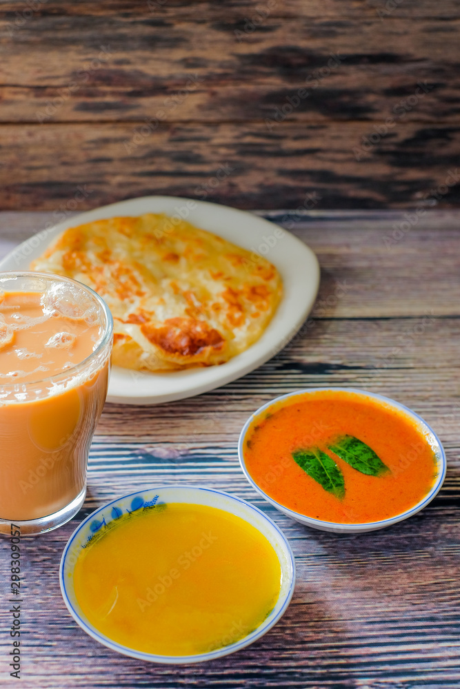 A cup of hot coffee , Roti canai or Roti Parata , dalca and curry sauce on wood background A cup of hot coffee , Roti canai or Roti Parata , dalca and curry sauce on wood background