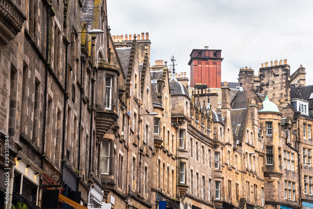 Trditional town houses with shops at the ground level in Edinburgh Old Town and cloudy sky
