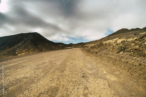 Off road country way at the mountain - dramati sky at the horizon - concept of adventure and travel - alternative place and vacation for nomad people