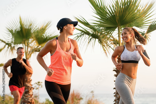 Happy sportswomen communicating while running in nature.