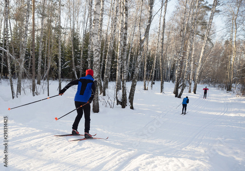 Group cross-country skiing in the park. Sunny day, competitive spirit.