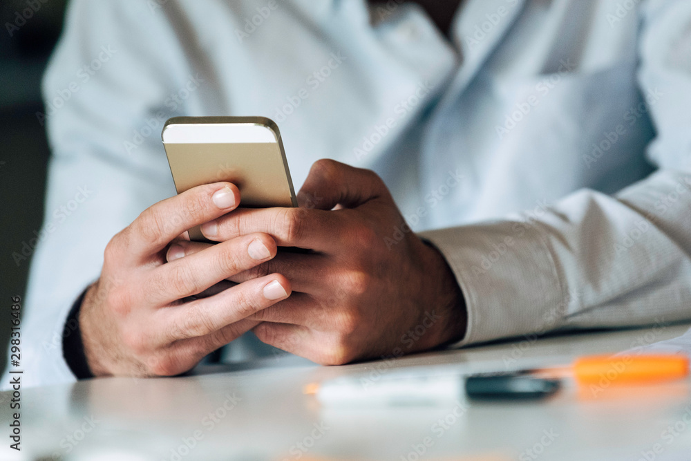 Close-up of young businessman's hands using smartphone in office Close-up of young businessman's hands using smartphone in office