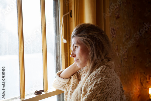 Fényképezés Side view of thoughtful woman with blanket looking through window while standing