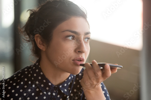 Fotografie Indian woman recording audio message or using voice recognition