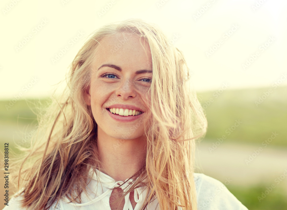 happiness, country, summer holidays, vacation and people concept - close up of happy smiling young woman or teenage girl with wild hair outdoors